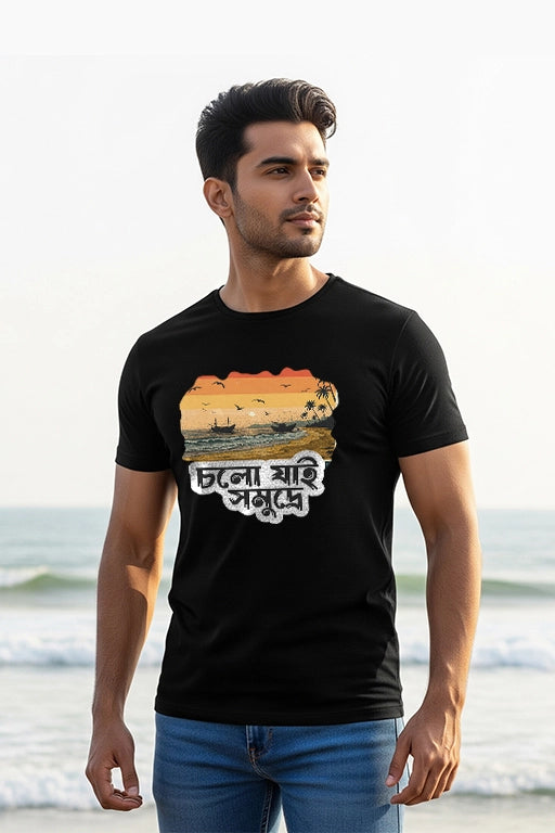 Man wearing a black t-shirt with a sunset design and text on a beach