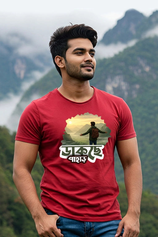 Man wearing a red t-shirt with a graphic design in front of a mountainous landscape