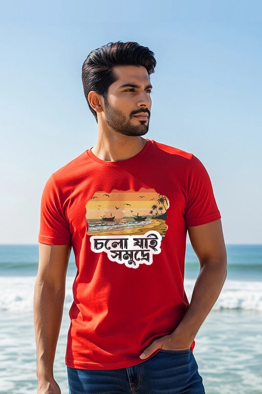 Man wearing a red t-shirt with a graphic design and text, standing on a beach.