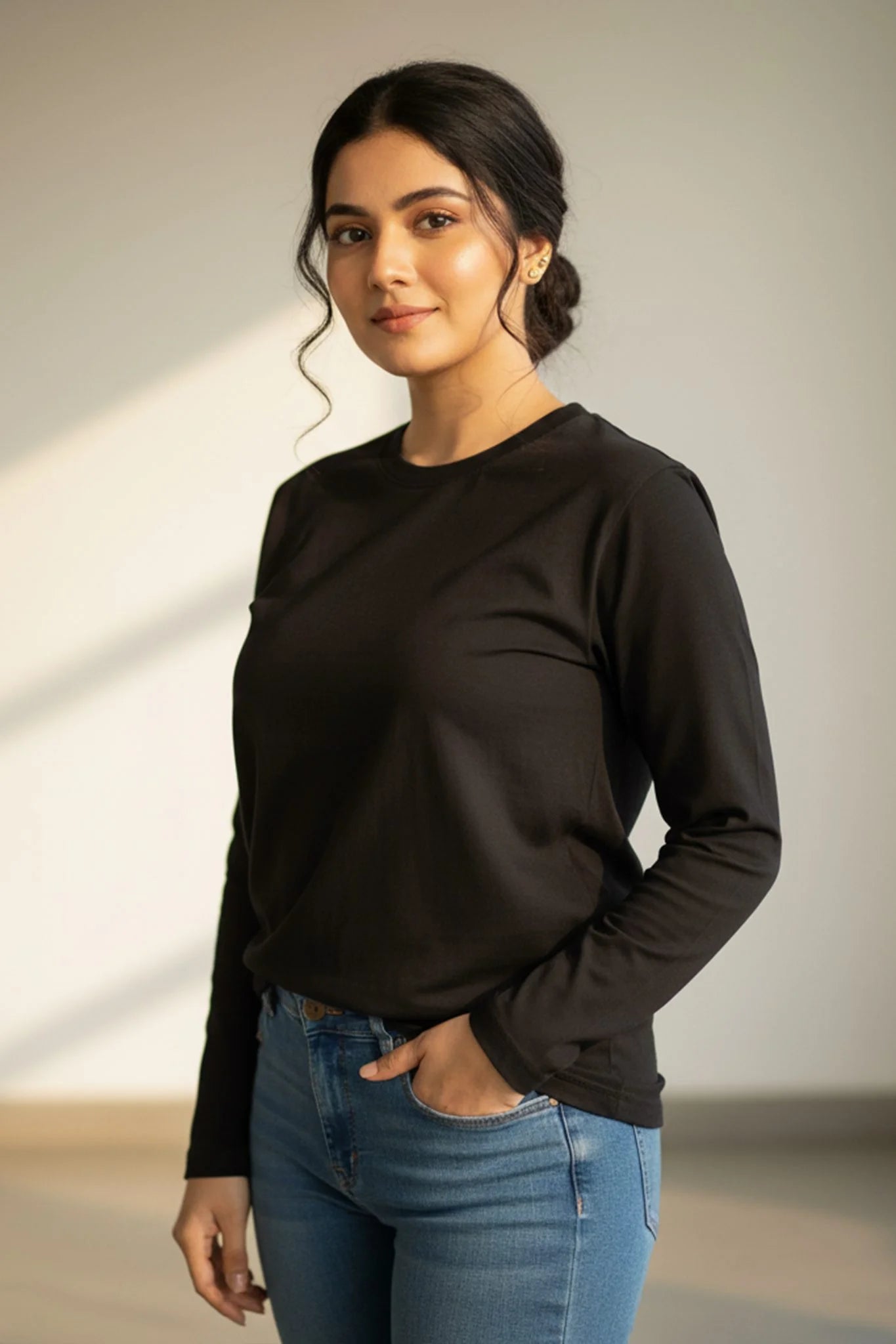 Woman wearing a black solid full sleeve top from KRAZYKIND, showcasing a stylish, fitted long sleeve shirt.