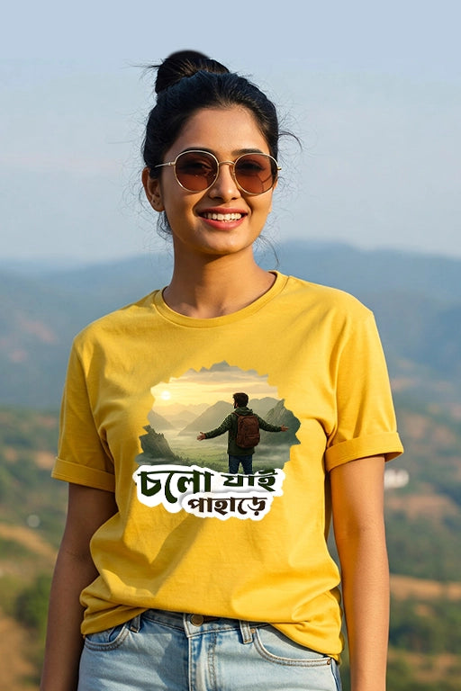 Person wearing a yellow t-shirt with a graphic and text, standing against a mountainous background.